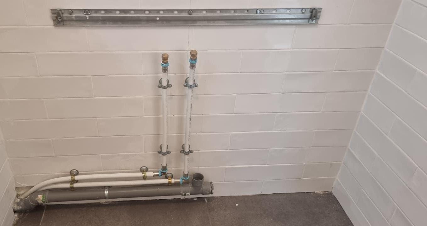 Nouvelles arrivées d'eau et évacuations installées le long d'un mur carrelé