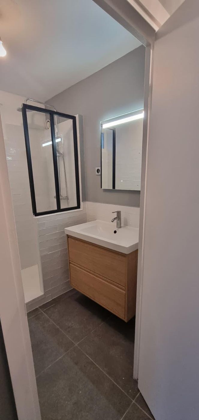Petite salle d'eau avec douche et verrière d'atelier noire, meuble vasque bois et sol gris